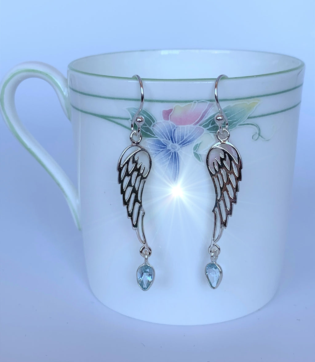 Pear shaped blue topaz dangle from open sterling silver angel wings. These earrings are lightweight, have wires, not posts for wearing and are approximately 1 ¾" long.