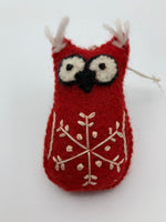 Load image into Gallery viewer, This is a close-up view of the red owl Christmas ornament that is handcrafted (fair trade) and made of 100% hand-felted natural wool. It is red with black and white accents and tufts of white hair on its ears &amp; has a &#39;signature&#39; (white) snowflake on its belly. Approximately 4&quot;x2.5&quot;. Comes with a fair trade holiday &quot;to/from&quot; tag to use if giving this as a gift.
