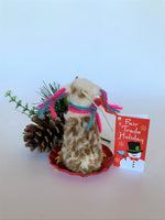 Load image into Gallery viewer, This is a back view of the sledding llama Christmas ornament that is handcrafted (fair trade) and is made of 100% natural, hand-felted wool. The sled is handmade using paper and feels something like very thin wood. The llama is furry, off-white and brown, with black accents (hooves, facial features), sits on a round red sled and wears a scarf made of colorful (red, blue and pink) yarn. The same yarn is used for accents on its ears. Approximately 4.5&quot;x2.75&quot;x2.75&quot;.
