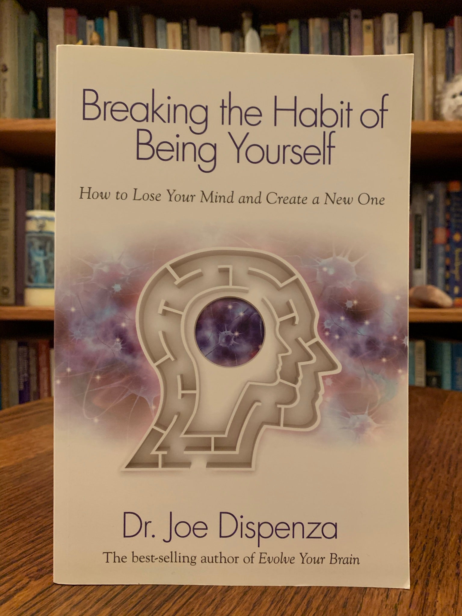 Close-up of Front cover of "Breaking the Habit of Being Yourself" by Dr. Joe Dispenza. As you read this book, "not only will you be given the necessary knowledge to change any aspect of yourself, you will be taught the step-by-step tools to apply what you learn in order to make measurable changes in any area of your life...[Dispenza] combines the fields of quantum physics, neuroscience, brain chemisty, biology and genetics to show you what is truly possible. Cost is $16.99
