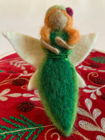 Load image into Gallery viewer, This close-up view of the earth fairy Christmas ornament is handmade (fair trade) from 100% wool. She is tan skinned &amp; wearing a dark green dress with light green on the edge &amp; has a double row of tiny green beads around the empire waist. She wears a light green hat with a red flower on it, has orange hair and white wings with a bit of light yellow on them. She has bendable arms and no facial markings. She is approximately 5&quot;x2.5&quot; and comes with a fair trade holiday &quot;to/from&quot; tag to use if giving as a gift.
