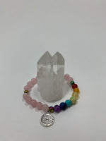 Load image into Gallery viewer, Rose quartz gemstone power bracelet, accented with 7 gemstone beads to match the chakras. It has 3 accent beads - silver colored or rainbow-ish colored (these are not gemstones). The bracelet also includes a silver-colored lotus charm (not sterling silver). The gemstones are genuine, but the color has been enhanced on this line of power bracelets. There are other bracelets  available in the store with the natural color only.
