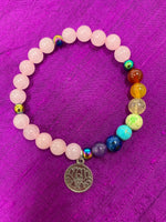 Load image into Gallery viewer, Second close-up view of the quartz gemstone power bracelet, accented with 7 gemstone beads to match the chakras. It has 3 accent beads - silver colored or rainbow-ish colored (these are not gemstones). The bracelet also includes a silver-colored lotus charm (not sterling silver). The gemstones are genuine, but the color has been enhanced on this line of power bracelets. There are other bracelets available in the store with the natural color only.
