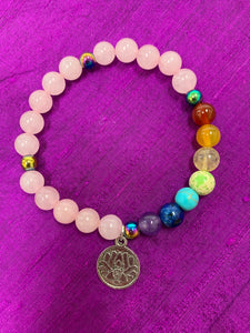 Second close-up view of the quartz gemstone power bracelet, accented with 7 gemstone beads to match the chakras. It has 3 accent beads - silver colored or rainbow-ish colored (these are not gemstones). The bracelet also includes a silver-colored lotus charm (not sterling silver). The gemstones are genuine, but the color has been enhanced on this line of power bracelets. There are other bracelets available in the store with the natural color only.