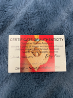 Load image into Gallery viewer, Close-up of the &quot;Certificate of Authenticity&quot; for the beautiful smudging feather with its shaft wrapped in leather and accented by colorful beads. It shows that this is an authentic Native American made product. 

