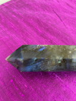 Load image into Gallery viewer, View of blue on end of wand. Double terminated labradorite wand. Labradorite is a very special and amazing gemstone and is known for its beauty, much of which comes from an iridescent quality it possesses. This quality is created by fractures within the stone, that reflect various colors, such as blue, green, red, yellow &amp; orange. Labradorite brings light, raises consciousness, deflects negative energies and releases fear &amp; insecurity (and more). Approx. 3¾&quot; long. Cost is $22.
