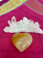Load image into Gallery viewer, Reverse side. Beautiful citrine (yellow quartz) heart! Great to place on your altar or bookshelf, to hold during meditation, to use for healing or as a décor item in your home of office. Citrine absorbs and dispels negative energy, is a stone of abundance - attracting money, prosperity and success, warming &amp; energizing, enhances creativity, brings a positive attitude, is cleansing and more. This citrine heart is approximately 2&quot; at it&#39;s widest expanse. Cost is $24.
