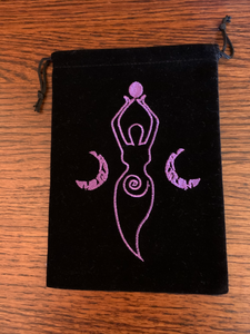 Close-up view of front of bag. Lovely oracle/tarot deck bag with drawstrings for closure. Black faux-velvet with purple embroidered Moon goddess. She holds a small moon in her hands, above her head. There is a crescent moon on either side of her and a spiral on her lower body. This 7"x5" bag can hold almost any size oracle or tarot deck, but is best suited for larger decks (e.g. Medicine Cards). This bag can also be used to store large crystals or other precious items. Cost is $7.50