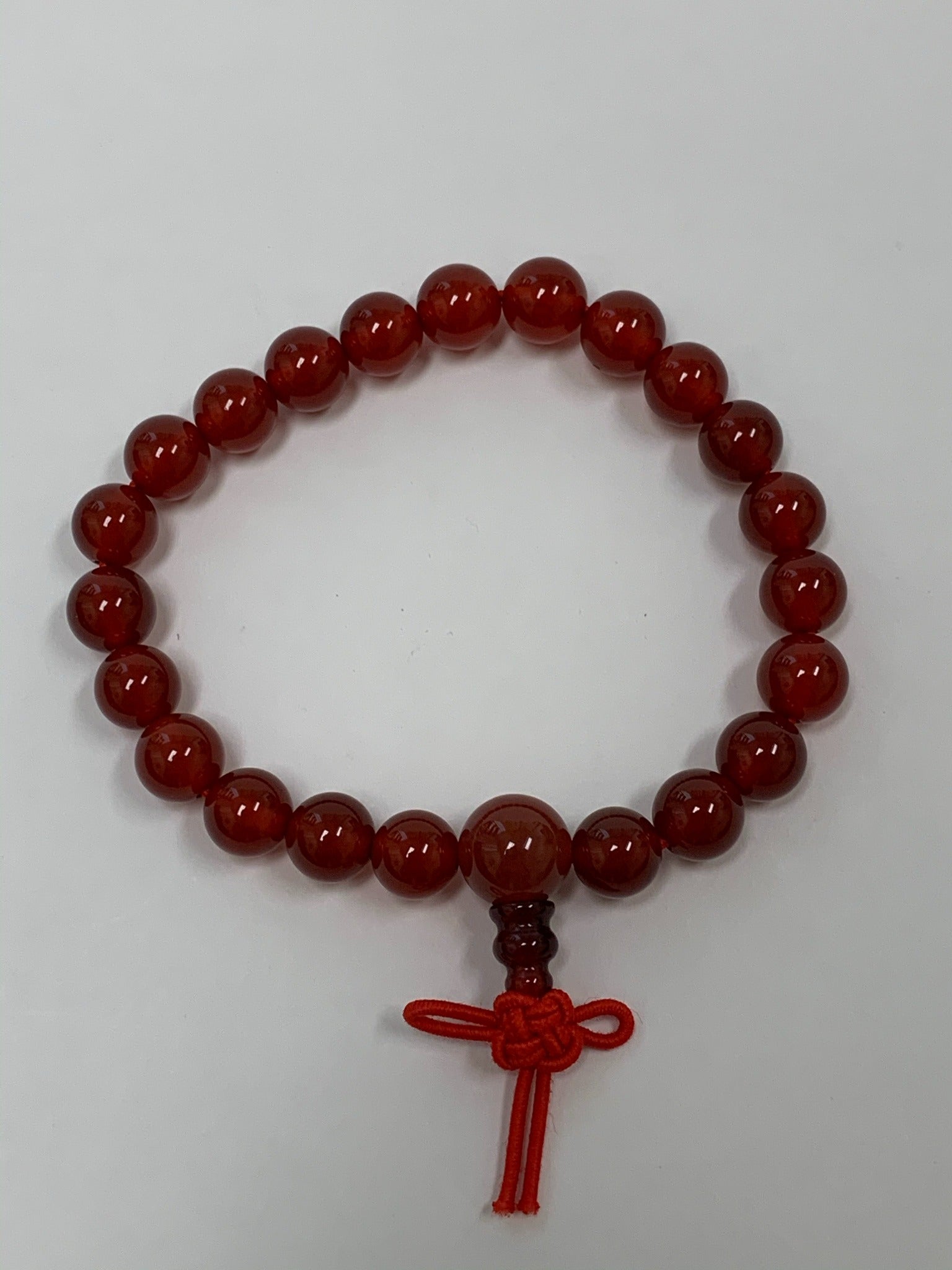 Close-up view. Carnelian power bracelet accented with red Chinese tassel knot. Beads are 8 mm. Carnelian promotes courage, creativity, vitality and dispels emotional negativity.