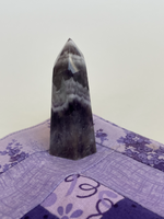 Load image into Gallery viewer, Alternate view. Chevron amethyst tower with the coolest banding for your altar, for healing or as décor for any room in your home or office. Amethyst, one of the most spiritual gemstones, heals, cleanses &amp; calms, allowing you to reach meditative &amp; higher consciousness levels more easily. It also helps to dispel negative emotional states and more. Chevron amethyst is a combination of amethyst and white quartz and when you add the quartz you get additional qualities. Approx. 2¼&quot; long. Cost is $13.20.

