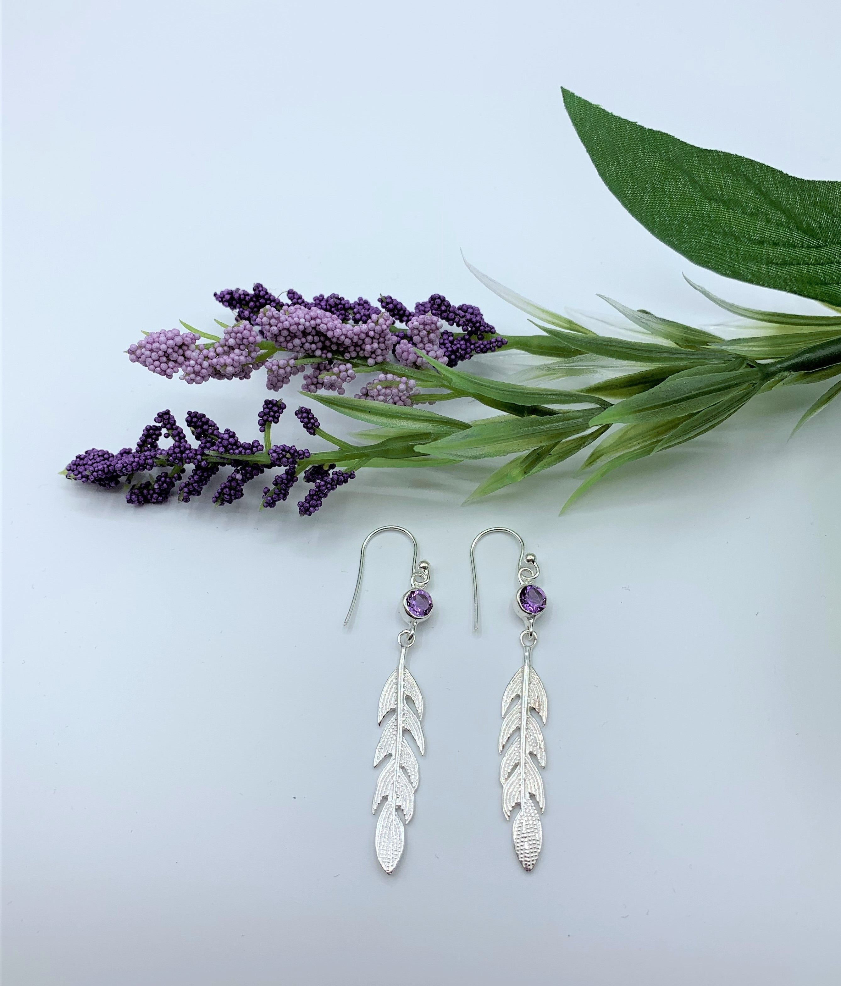 Another view of the round faceted amethyst gemstones set in sterling silver (one in each earring) with long sterling feathers dangling below them. These have wires, not posts and are approximately 2" long.