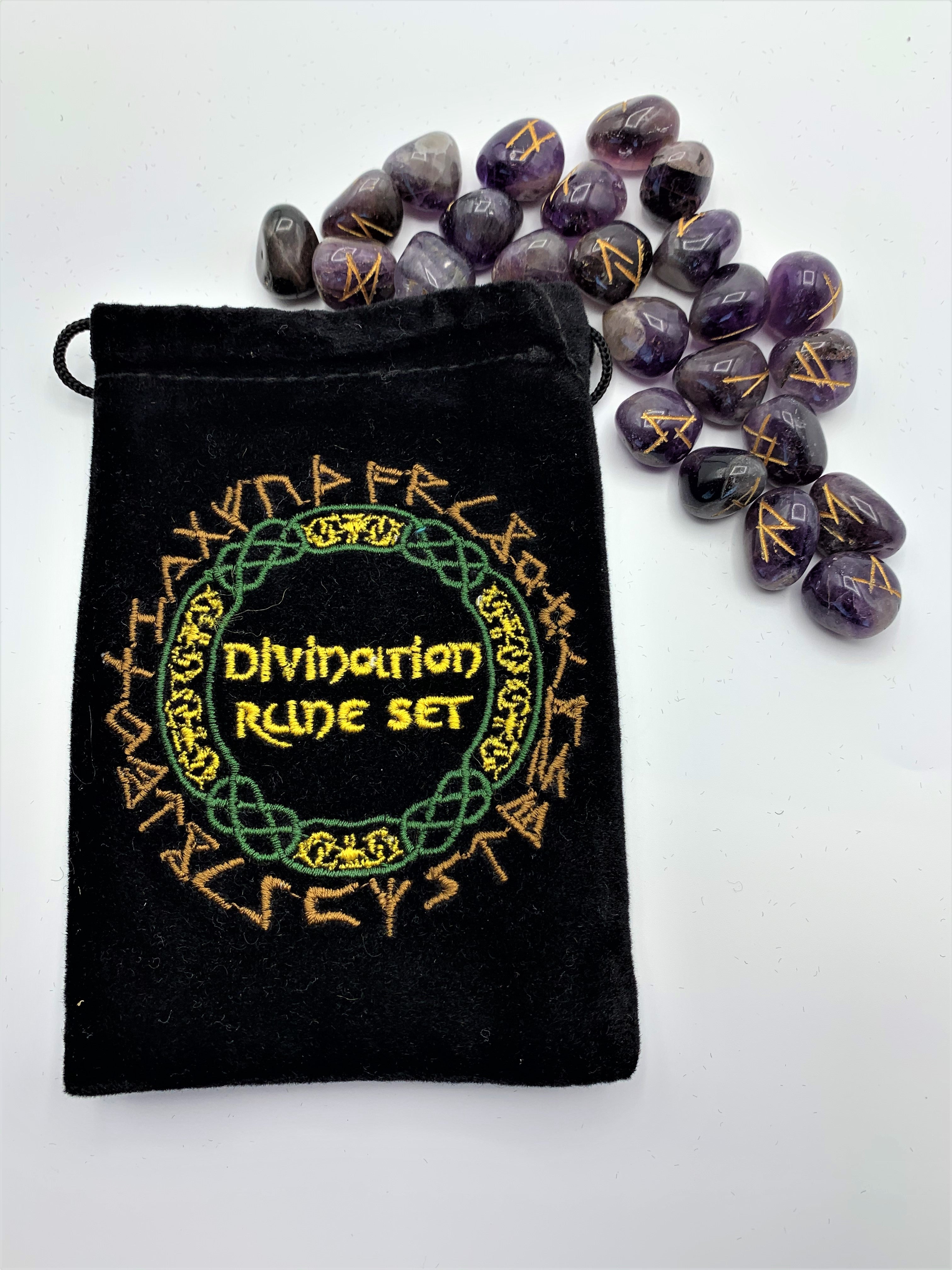 Close-up view of the amethyst Rune set with a runic symbol (in gold) on each stone. The set comes in a black bag embroidered on the front in green, yellow and light brown/gold with runic designs and the words "Divination Rune Set." Comes with a rolled up sheet of paper displaying each rune and its meaning.