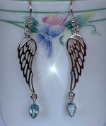 Load image into Gallery viewer,  Close-up view. Pear shaped blue topaz dangle from open sterling silver angel wings. These earrings are lightweight, have wires, not posts for wearing and are approximately 1 ¾&quot; long.
