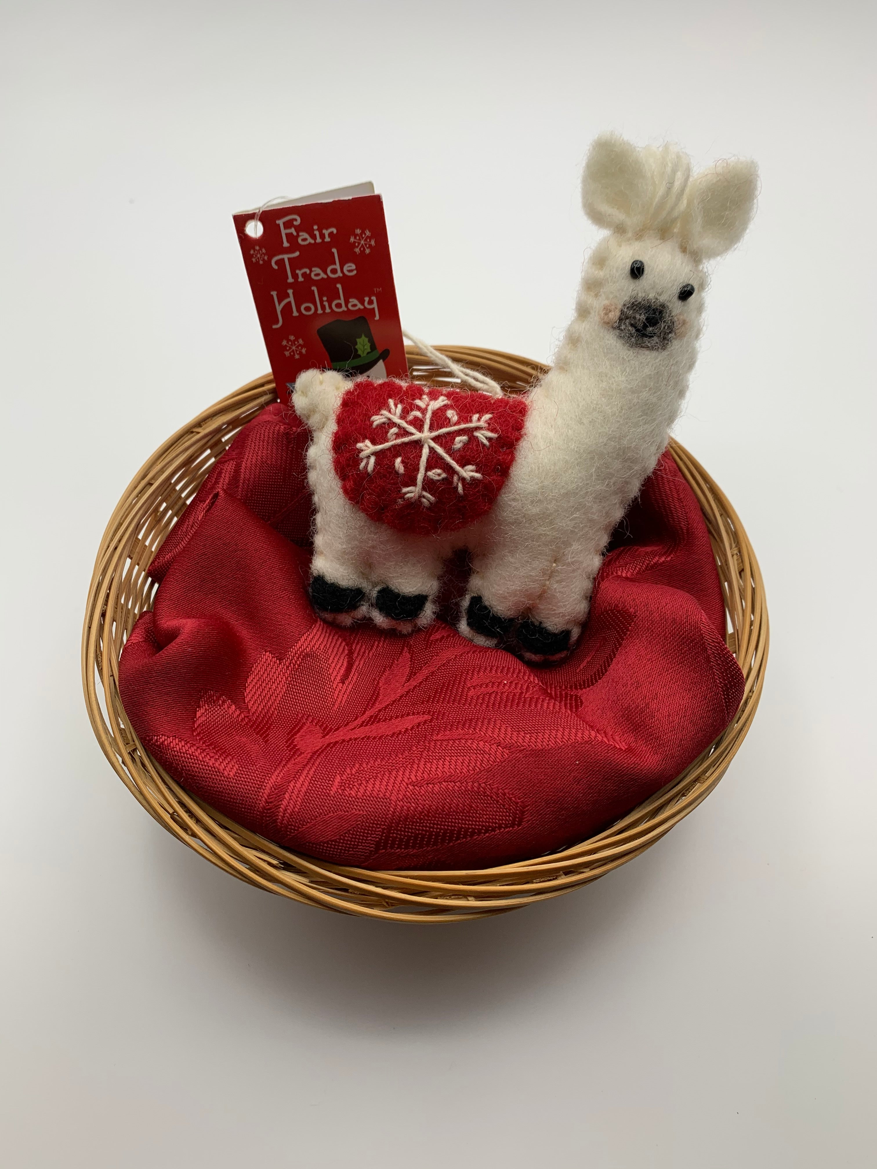 This llama Christmas ornament is hand-crafted (fair trade)  and made of 100% natural hand-felted wool. It is off-white with a gray muzzle and black accents (hooves, nose, etc.) has a cute tuft of (yarn) hair between his ears & wears a rounded red blanket on its back with a 'signature' (white) snowflake on it. It is approximately 4.5"x3.5".  It comes with a detachable fair trade holiday "to/from" tag to use is giving as a gift.