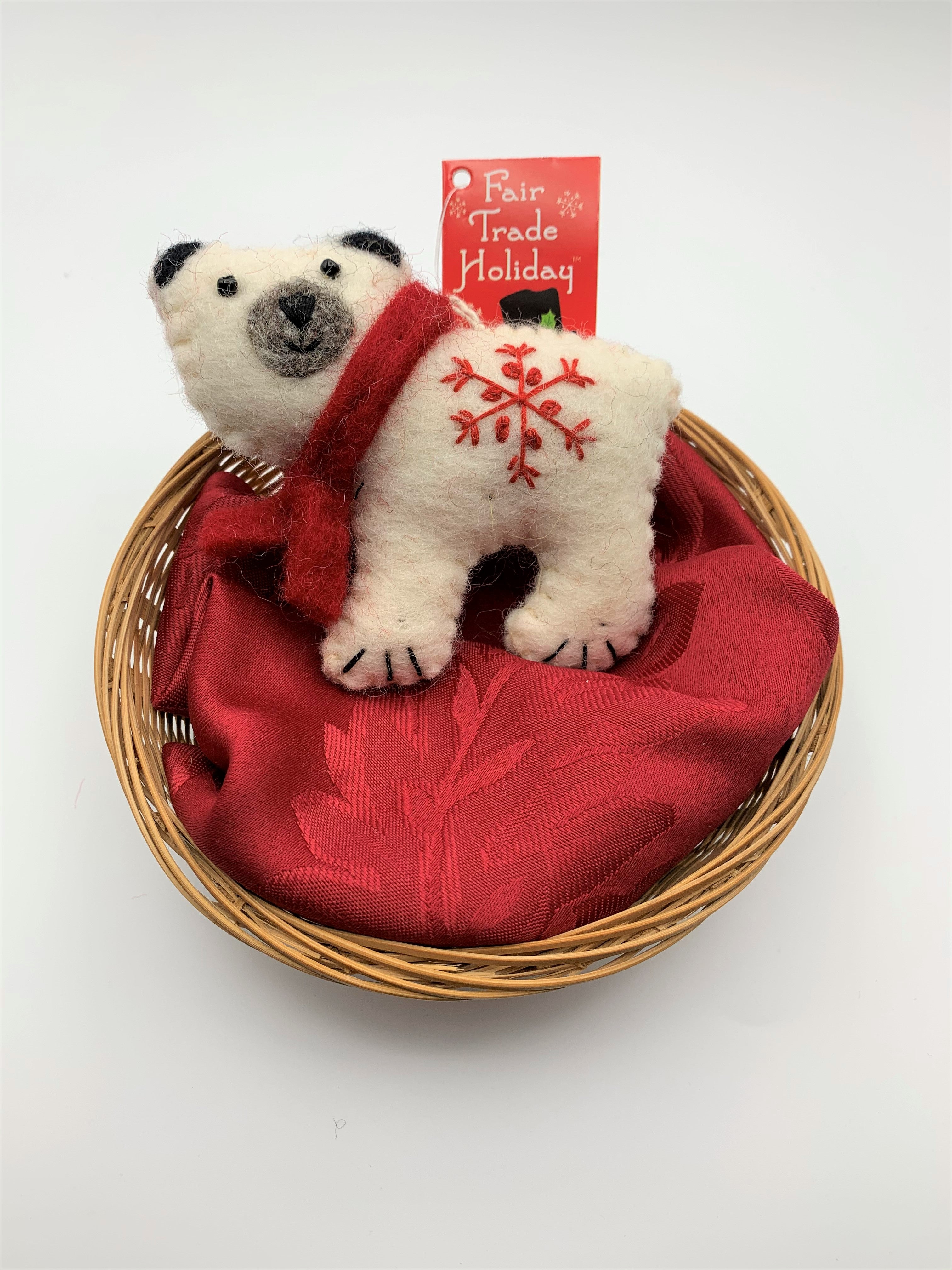 This is a polar bear Christmas ornament that is hand-crafted (fair trade) and made of 100% natural wool. It is off-white with a gray muzzle and black accents (ears, eyes, etc.) and wears a red winter scarf. He has a 'signature' (red) snowflake on his body. Approximately 3.75"x4.2". It comes with a fair trade holiday "to/from" tag to use if giving as a gift.