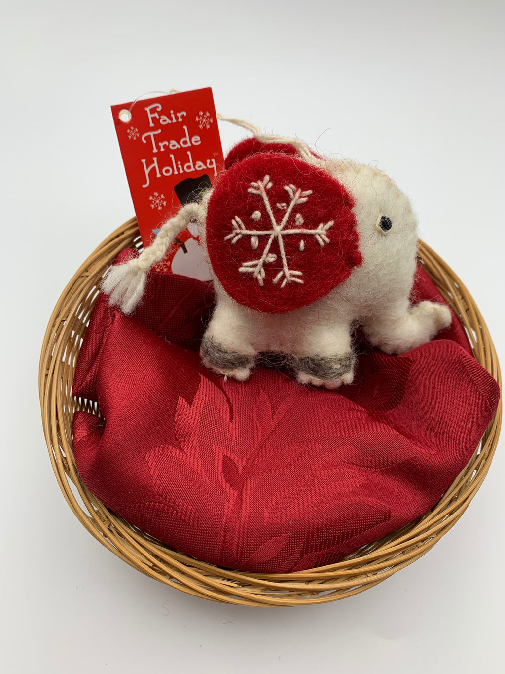 This is Jumbo the elephant, a Christmas ornament that is hand-crafted (fair trade) and is made of 100% natural wool.  He is off-white with large red ears and black accents (feet, eyes, etc.). The 'signature' (white) snowflake is on his ear.  He is approximately 3"x3.25" (his tail adds another 1.75"). He comes with a fair trade holiday "to/from" tag to use if giving this as a gift.