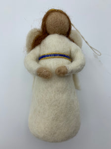 This is a close-up photo of the angel Christmas ornament that is handmade (fair trade) and made of 100% natural wool. She is brown-skinned, wears an off-white dress with blue and gold beading around the empire waist, has off-white wings, a gold beaded halo and bendable arms. Approximately 5"x2.75". She comes with a fair trade holiday "to/from" tag to use if giving this as a gift.