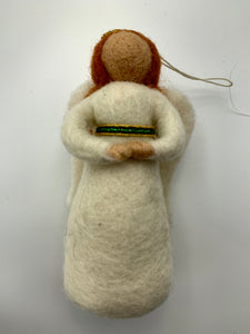 This is a close-up photo of an angel (light skin) Christmas ornament, handcrafted (fair trade) and made of 100% natural wool. She wears a white dress with gold & green beading around an empire waist, has white wings, a gold beaded halo and bendable arms. Approximately 5" tall. She comes with a detachable fair trade holiday tag to use if you are giving this as a gift.