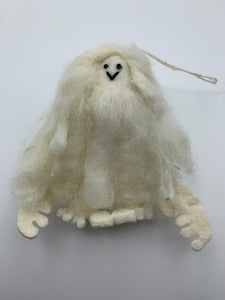 This is a close-up photo of the Yeti Christmas Ornament that is handcrafted (fair trade) and made of 100% natural wool. He is off-white and furry with felted hands and feet and black accents (mouth/eyes). Approximately 4.5"x3.5". He comes with a fair trade holiday "to/from" tag to use if you are giving this as a gift.