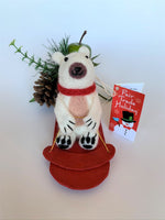 Load image into Gallery viewer, This sledding polar bear Christmas Ornament is handcrafted (fair trade). The polar bear is made of 100% natural wool and the sled is handmade with paper that is hardened and feels somewhat like very thin wood and it is red.  The bear is off-white with a tan belly, brownish-gray muzzle, black accents (paws, nose, etc.) and is wearing a red winter scarf.  It is approximately 4.75&quot;x3.5&quot;x2.5&quot;. It comes with a fair trade holiday &quot;to/from&quot; tag to use if giving this as a gift.

