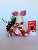 Load image into Gallery viewer, This is a back view of Piggles the sledding piggy Christmas ornament who is handcrafted (fair trade) and made of 100% natural wool. It sits on a round, red sled that is handmade using paper which is hardened and feels almost like thin wood. Piggles is off-white with pink ears, snout and with other pink and black accents (eyes, mouth, etc.). and wears a red &amp; white winter scarf. Approximately 4&quot;x2.75&quot;x2.5&quot;. She comes with a detachable fair trade holiday &quot;to/from&quot; tag to use if giving this as a gift.
