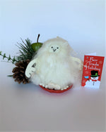 Load image into Gallery viewer, This is a sledding Yeti Christmas ornament that is handcrafted (fair trade) and made of 100% natural wool. The sled is handmade using paper that is hardened and feels almost like thin wood.  It is off-white with black accents (eyes and mouth), with off-white felted arms and feet. It sits on a round, red sled with gold colored &quot;rope&quot; handles  on either side.  Approximately 4.5&quot;x2.75&quot;x2.75&quot;.  It comes with a detachable fair trade holiday &quot;to/from&quot; tag to use if giving this as a gift.
