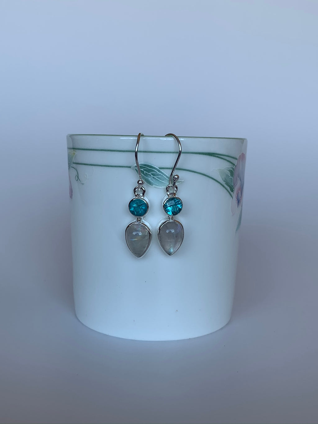 Sterling silver earrings with wires for wearing. Stones are small round faceted blue apatite with a reverse tear drop moonstone hanging below it.  Approximately 1½" long. Natural inclusions  & variations in stones are normal as each stone is unique. These beauties are handcrafted by artisans.