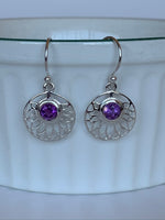 Load image into Gallery viewer, Close-up view of round amethyst gemstones are set into a delicate, open, sterling silver lotus pattern. These earrings are lightweight, have wires, not posts and are approximately 1½&quot; long.
