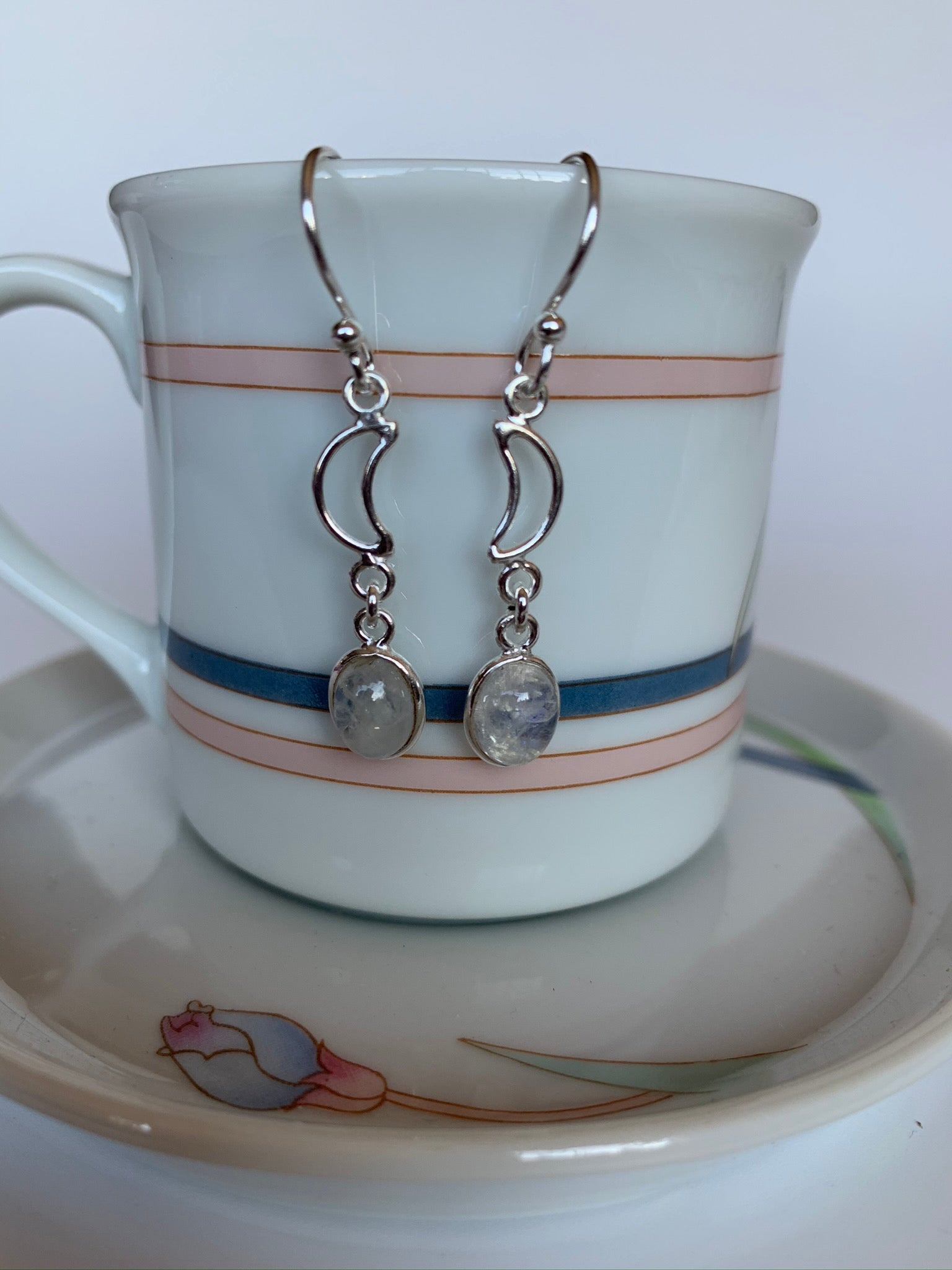 Delicate sterling silver earrings with small open crescent moon and dangling round moonstone set in sterling. These are lightweight and approximately 1½" long. Earrings have wires, not posts for wearing.