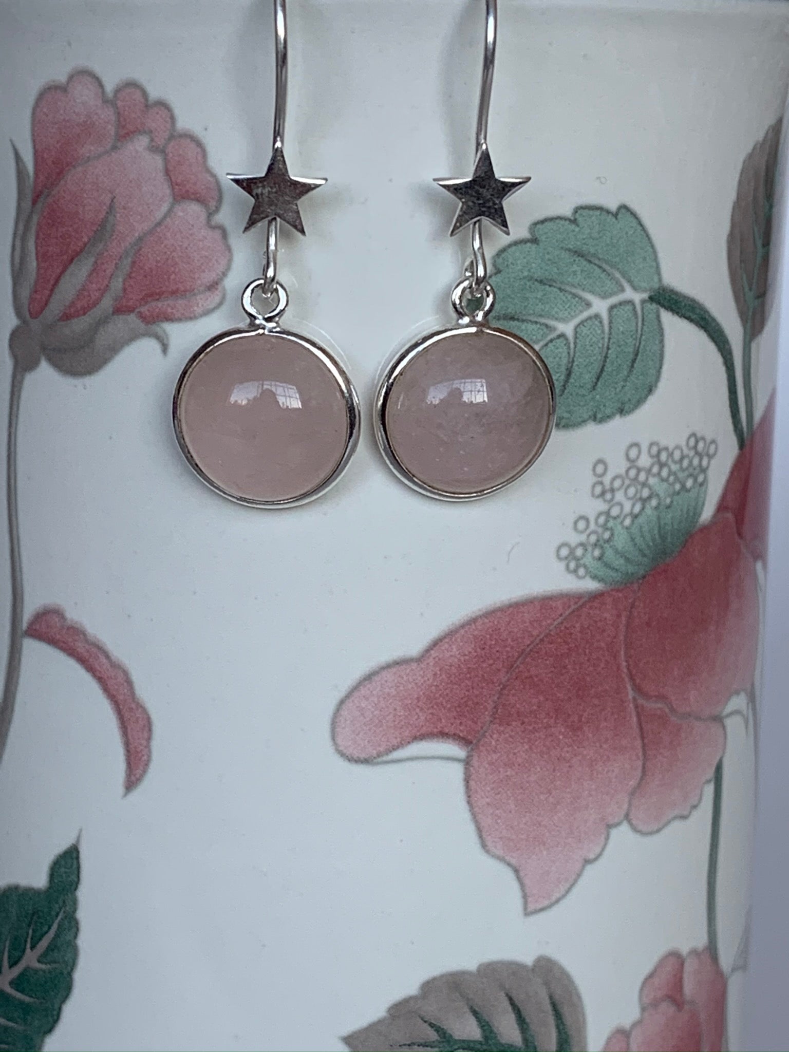 Close-up view. Good size, round rose quartz gemstones, set in sterling silver, dangle from a sterling silver star. These have wires, not posts, are lightweight and are approximately 1½" long.