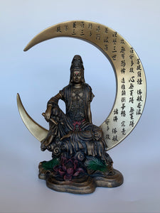 Beautiful, detailed statue of Kwan Yin sitting on a large crescent moon finished in a burnished bronze. Kwan Yin is a revered and powerful goddess. She symbolizes compassion, mercy and kindness.  The moon represents powerful feminine energy, intuition, emotions/feelings. Color is added to certain details on this lovely statue, adding to its appeal. Red and green are added to the lotus flower and leaves below her and red is added to her belt and forehead. Approximately 7¾" tall.