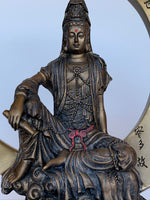 Load image into Gallery viewer, Close-up View of top of the beautiful, detailed statue of Kwan Yin sitting on a large crescent moon finished in a burnished bronze. Kwan Yin is a revered and powerful goddess. She symbolizes compassion, mercy and kindness.  The moon represents powerful feminine energy, intuition, emotions/feelings. Color is added to certain details on this lovely statue, adding to its appeal. Red and green are added to the lotus flower and leaves below her and red is added to her belt &amp; forehead. Approximately 7¾&quot;.
