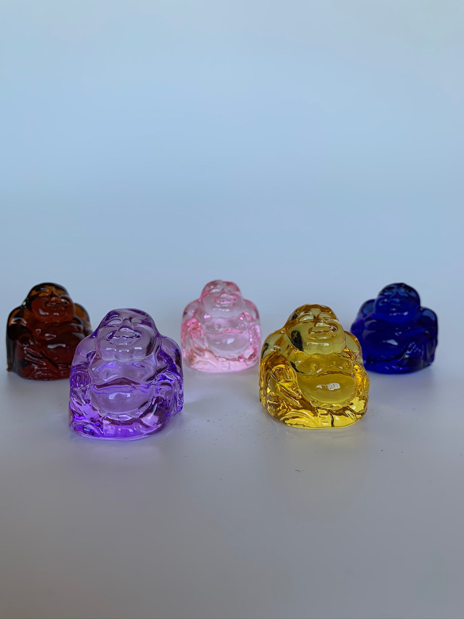 A Second view. Set of 5 Little glass Buddha statues in fun colors! Buy the set, give some away (or keep them all for yourself ;). Colors include purple, pink, amber, yellow/gold and blue. Buddha is revered around the world and his teachings and actions have shown us the beauty, wonder and power of enlightenment. The term Buddha refers to Awakened One.  Add one or more to your altar, meditation space or carry in your pocket or purse as a reminder of your spiritual journey.