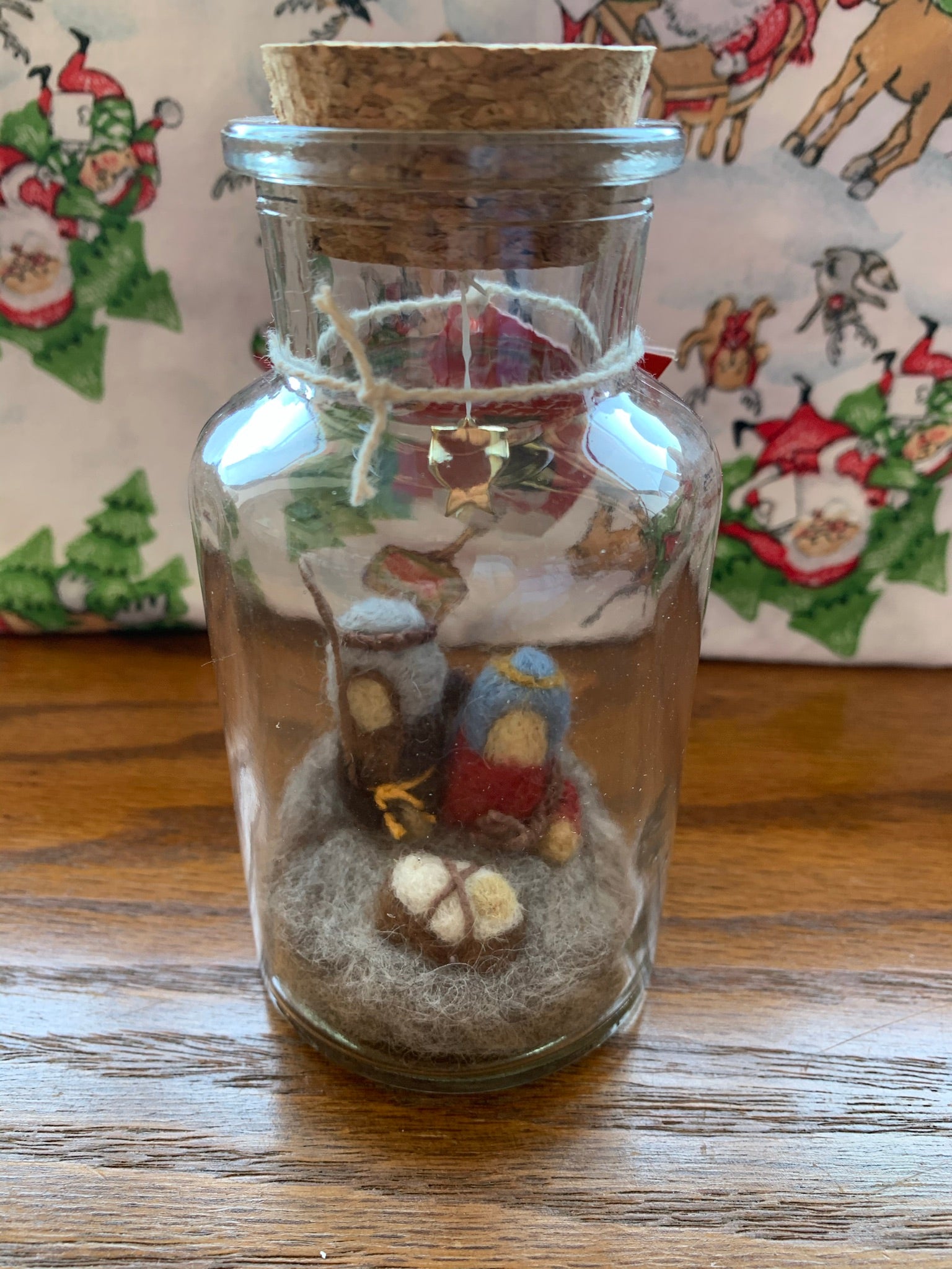 This Nativity story jar Christmas ornament displays Mary, Joseph and baby Jesus with a star above them, sitting on the ground. They sit inside a corked apothecary bottle. The Nativity is made of 100% natural wool. The bottle is affixed with a metal wire for hanging, but can also be placed on a shelf or table top. Approximately 3"x1" (6.75" if you include the wire hanger). It comes with a fair trade home and and garden tag.