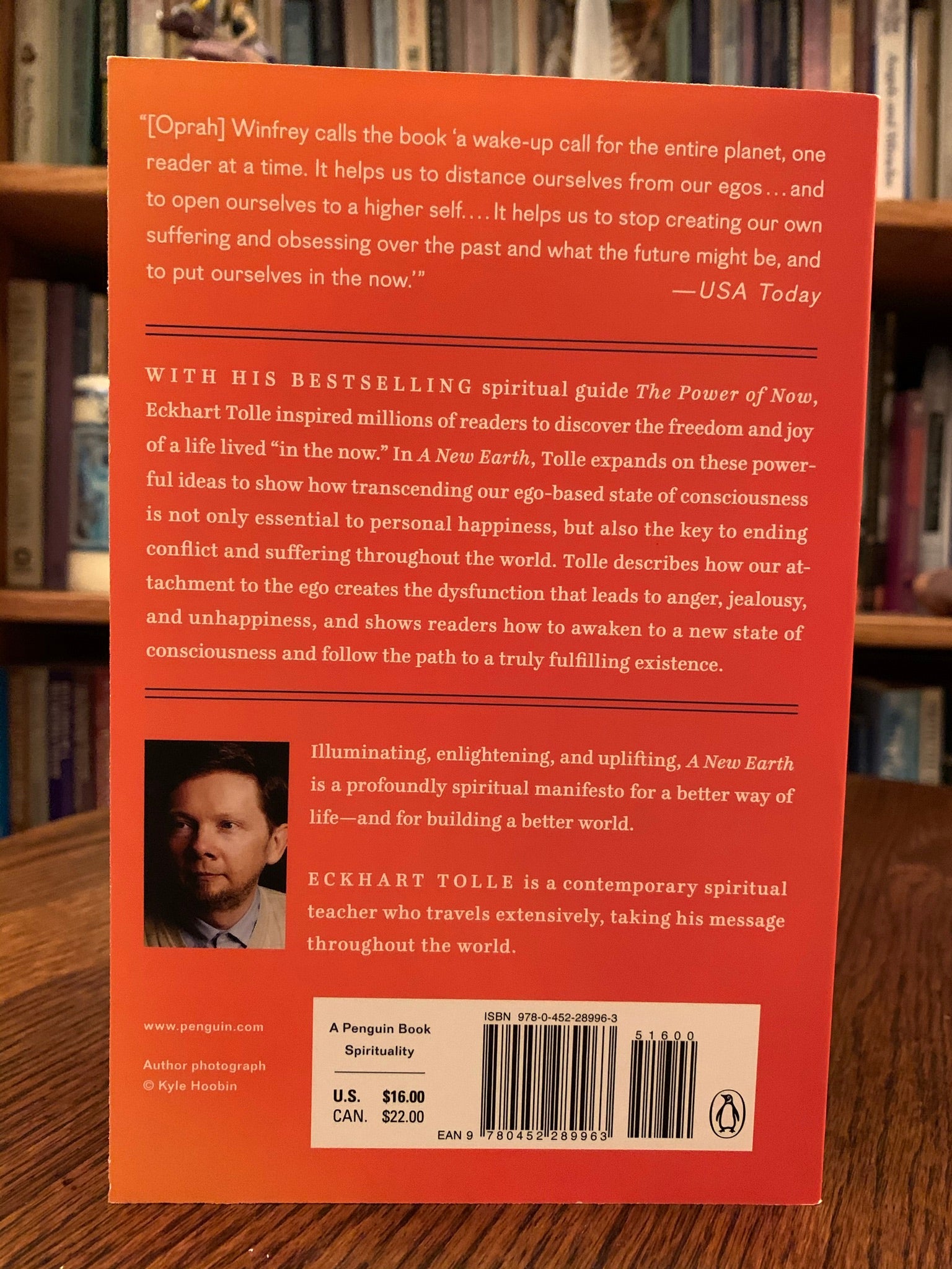 Close-up of back  cover of "A New Earth." In this book Tolle expands on ideas from his first book The Power of Now - "powerful ideas to show how transcending our ego-based state of consciousness is not only essential to personal happiness, but also the key to ending conflict and suffering throughout the world. Tolle describes how our attachment to the ego creates the dysfunction. His message is simple - stay conscious - in the present moment and don't allow the mind to lead you away from it. Cost is $17.00