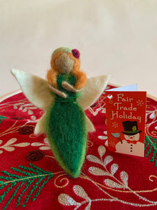 This earth fairy Christmas ornament is handmade (fair trade) from 100% wool. She is tan skinned & wearing a dark green dress with light green on the edge & has a double row of tiny green beads around the empire waist. She wears a light green hat with a red flower on it, has orange hair and white wings with a bit of light yellow on them.  She has bendable arms and no facial markings.  She is approximately 5"x2.5" and comes with a fair trade holiday "to/from" tag to use if giving as a gift.