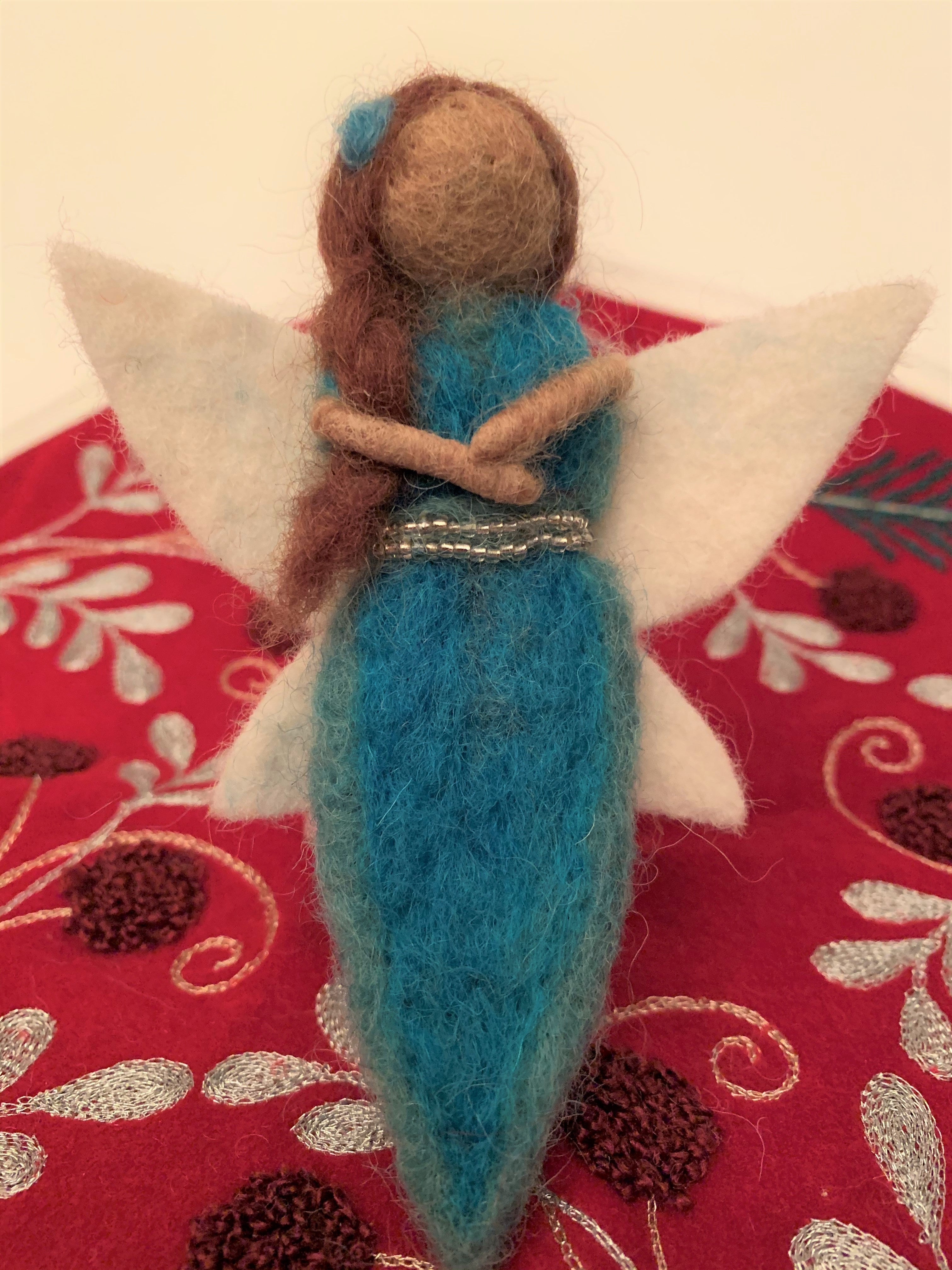 Close-up view. This sweet water-fairy Christmas Ornament wants to bring a little magic into your life. She is... ♥Handmade ♥Fair Trade (artisans who create these ornaments are paid fair wages for their work). ♥Made from 100% natural hand-felted wool ♥Approximately 5"x2.5" ♥One of the 4 fairy "elements" Christmas Ornaments. Buy one or collect them all. ♥Comes with a detachable "fair trade" holiday "to/from" tag to use if you are giving this as a gift. Cost: $11.00