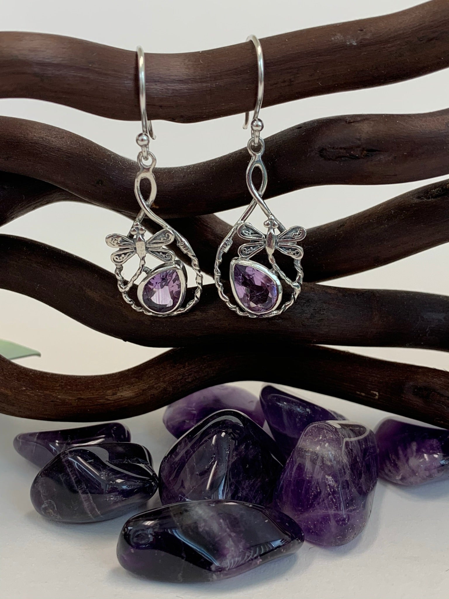 Teardrop shaped amethyst set, at a slant, at the bottom of an open tear drop shaped silver loop. sterling silver dragonflies "fly" above the amethysts. These beautiful and fanciful earrings are lightweight, have wires, not posts and are approximately 1½" long. 