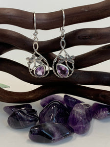 Teardrop shaped amethyst set, at a slant, at the bottom of an open tear drop shaped silver loop. sterling silver dragonflies "fly" above the amethysts. These beautiful and fanciful earrings are lightweight, have wires, not posts and are approximately 1½" long. 