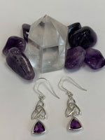 Load image into Gallery viewer, Close-up view. Trilliant cut (triangular) faceted amethyst gemstones outlined in sterling silver, dangle from an elongated Celtic trinity knot, or triquetra. These earrings are lightweight, have wires, not posts and are approximately 1½&quot; long.
