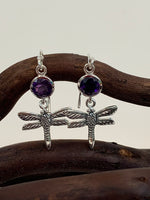 Load image into Gallery viewer, Round amethyst gemstones set above sterling silver dragonflies, which dangle below.  These earrings are lightweight, have wires, not posts and are approximately 1¼&quot; long.
