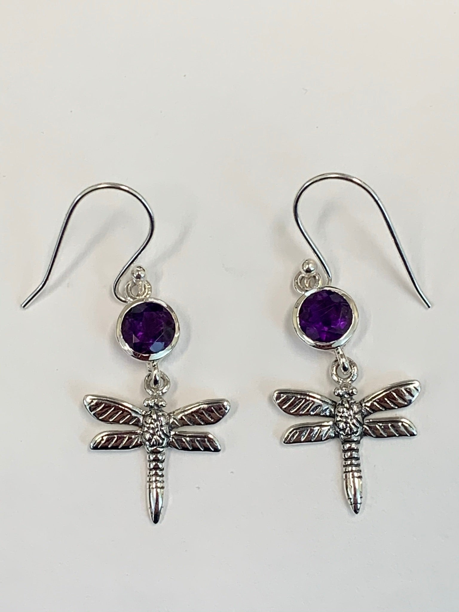 Close-up View. Round amethyst gemstones set above sterling silver dragonflies, which dangle below. These earrings are lightweight, have wires, not posts and are approximately 1¼" long.