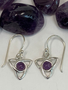 Close-up view. Round amethyst gemstones (cabs, not faceted) sit in the middle of a sterling silver Celtic trinity knot (or triquetra). These earrings are lightweight, have wires, not posts and are approximately 1¼" long.
