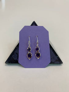 Two amethyst gemstones are set into each of the sterling silver earrings in a "twister" setting (like a stylized figure 8), one in the top part of the eight and one in the bottom. These earrings are lightweight, have wires, not posts and are approximately 1¼" long. 
