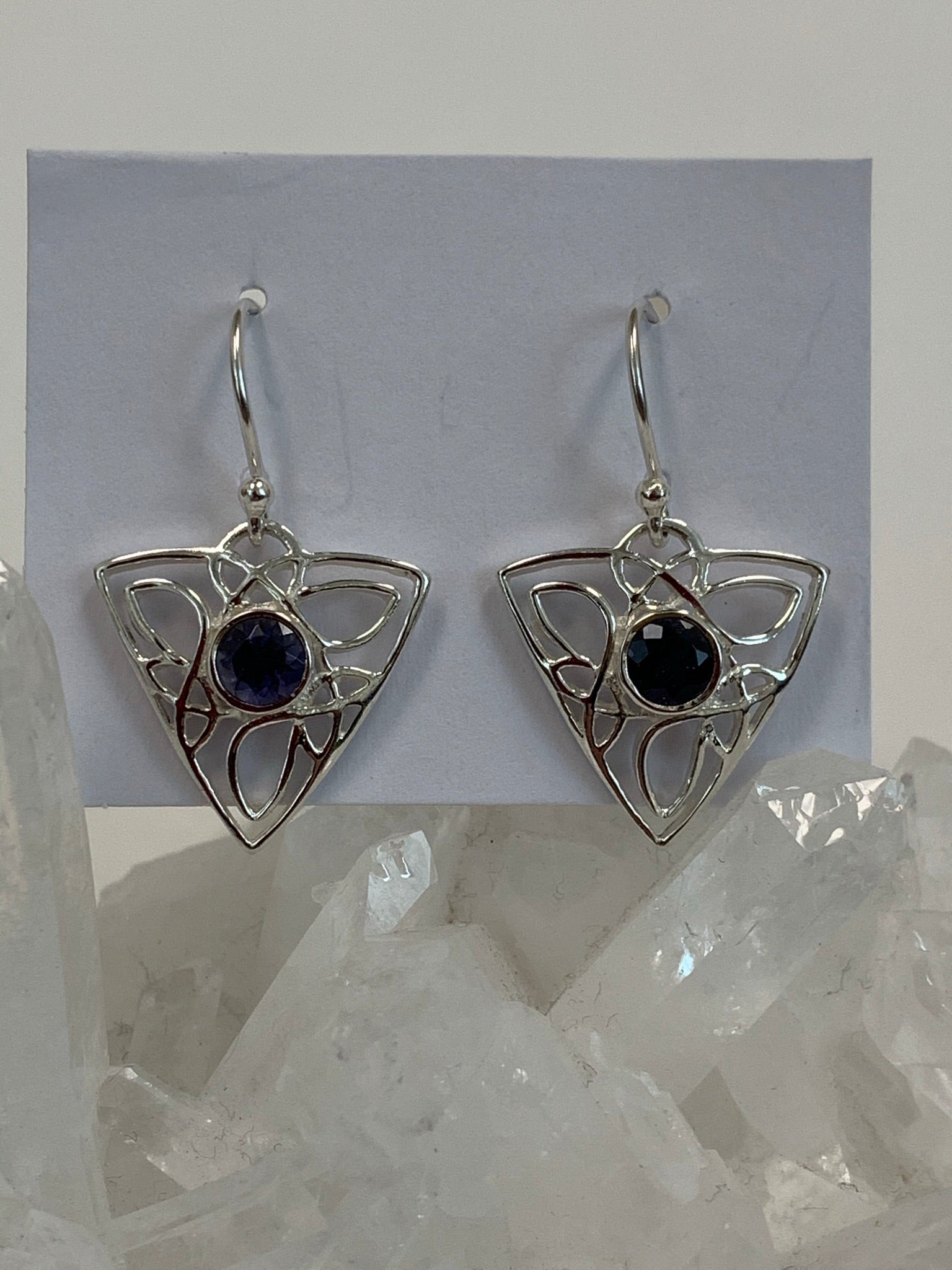 Close-up view. Faceted blue iolite gemstones are set in the middle of a fancy and flowing sterling silver Celtic knot. These earrings are lightweight, have wires, not posts and are approximately 1½" long.