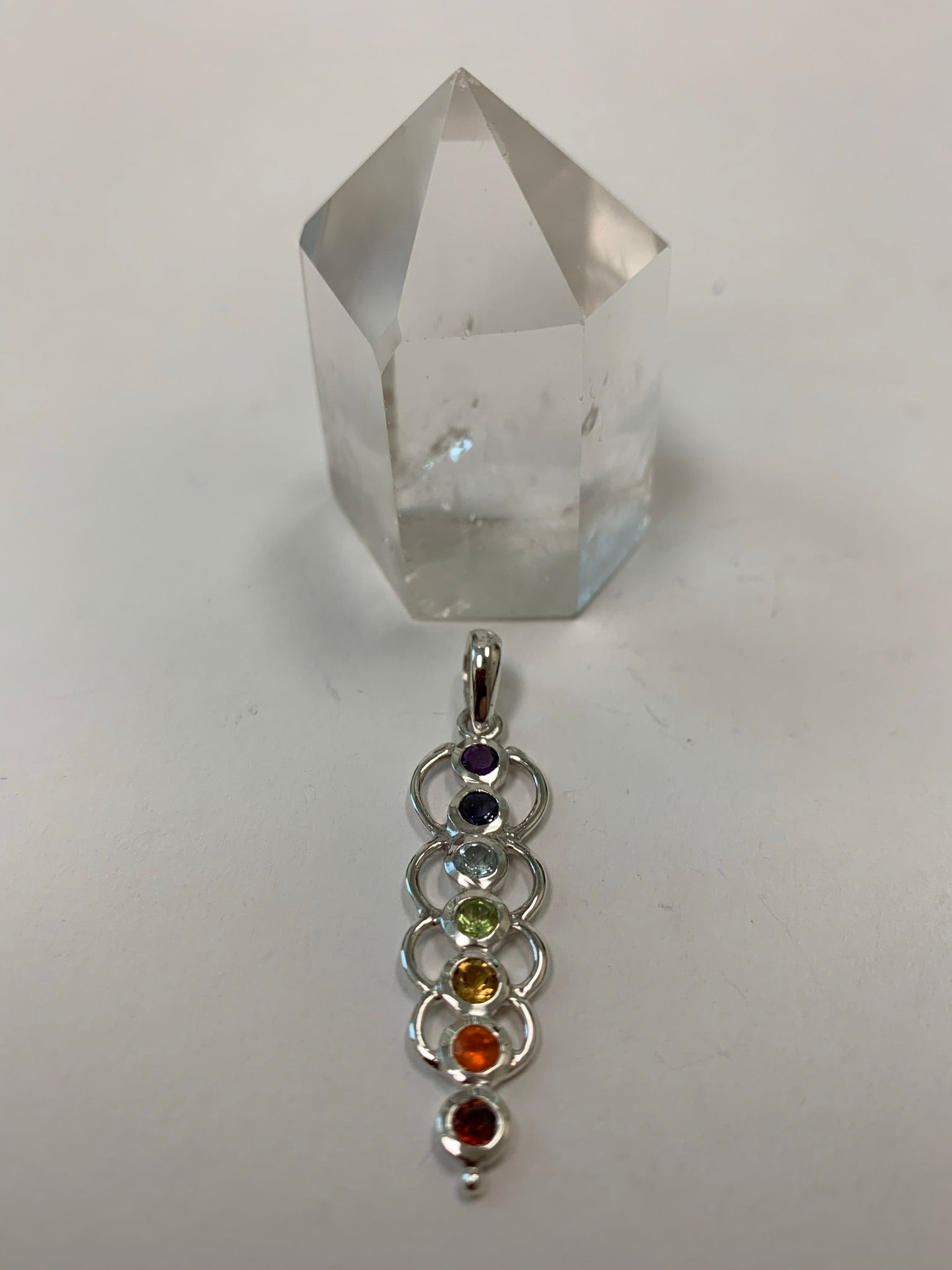 Another view of Chakra energy link pendant. Small faceted stones that represent each of the chakras: amethyst/crown, iolite/third eye, blue topaz/throat, peridot/heart, citrine/solar plexus, carnelian/sacral (or naval), garnet/root (or base). These stones, set in links or loops of sterling silver, two per loop or link, go straight down the middle. Pendant is approximately 1¾".