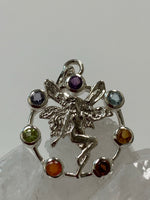 Load image into Gallery viewer, Close-up view. Chakra fairy pendant. Small faceted stones represent each of the chakras: amethyst/crown, iolite/third eye, blue topaz/throat, peridot/heart, citrine/solar plexus, carnelian/sacral (or naval), garnet/root (or base). These small, faceted stones are set around an open sterling silver circle. A sterling silver fairy extends through the center of the circle. Her wings reach a bit beyond the top of the circle and her feet touch the bottom. Pendant is approximately 1&quot;.
