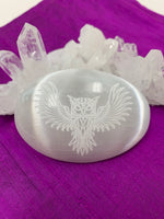 Load image into Gallery viewer, Owl etched on smooth, polished selenite palm stone from our Spirit Animal collection. Selenite ranges from translucent to milky white and is the perfect size to fit in your palm. Average weight is 4.2 oz and it is approximately 3&quot;x2.5&quot;. This selenite is ethically sourced and workers receive living wages.
