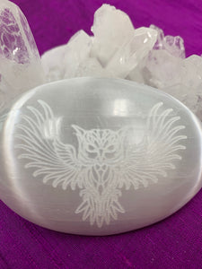 Close-up view of an owl etched on smooth, polished selenite palm stone from our Spirit Animal collection. Selenite ranges from translucent to milky white and is the perfect size to fit in your palm. Average weight is 4.2 oz and it is approximately 3"x2.5". This selenite is ethically sourced and workers receive living wages.