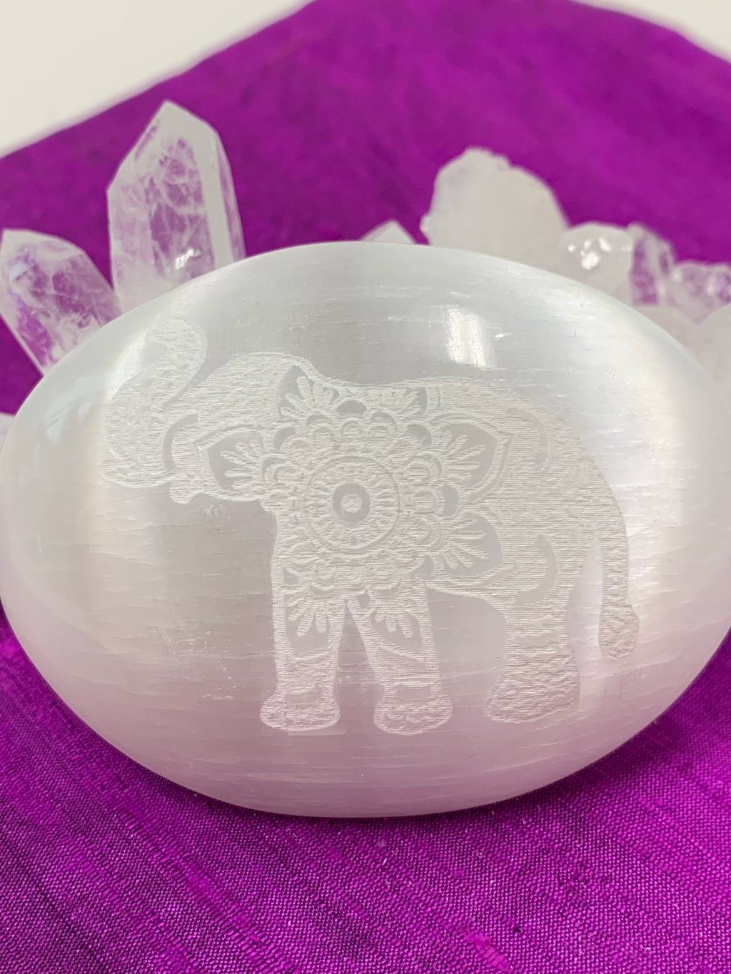 Ornately designed elephant etched on a smooth, polished selenite palm stone. The selenite stone can range from translucent to milky white in color. The weight of the stone varies, but the average weight is 4.2 oz and the average size is 3"x2.5", the perfect size to hold in the palm of your hand. These selenite stones are handmade and ethically sourced - workers are paid living wages.